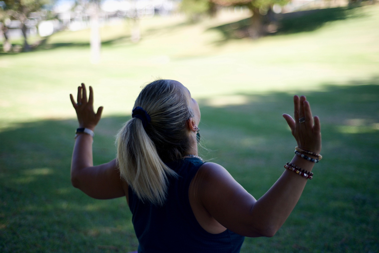 Sue from behind in yoga pose with chest open and hands up